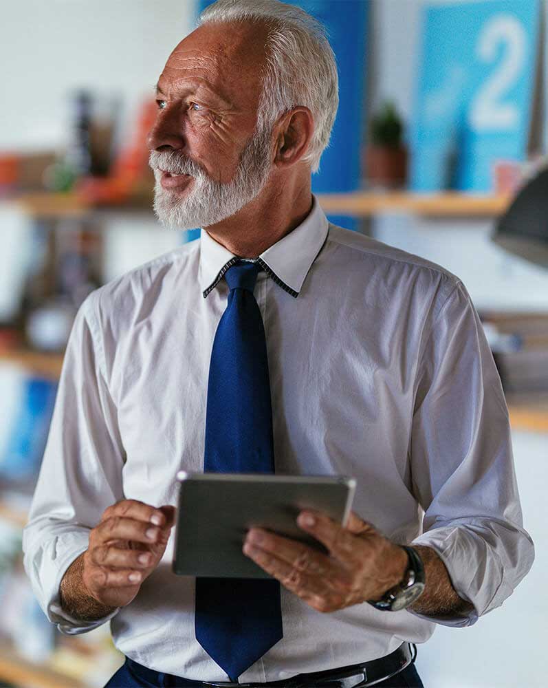 Older Man wearing a shirt and tie holding a tablet