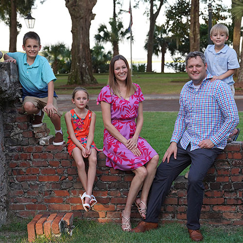 Casey Short posing with his family sitting along on a brick wall 