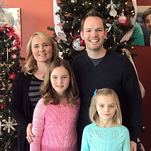 Tony Rizzo standing with his wife and two daughters in front of a Christmas tree